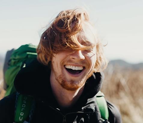 A man outside smiling with a hiking pack on.