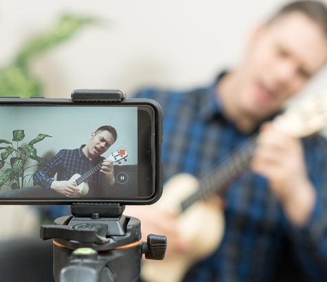 A man recording himself playing the guitar with his phone.